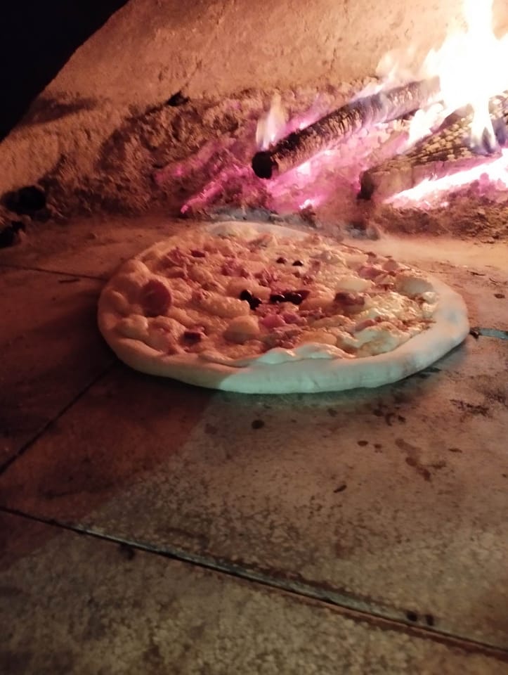 Pizza en cuisson au cœur des flammes du four à bois Pizzas Popeye à Pignans