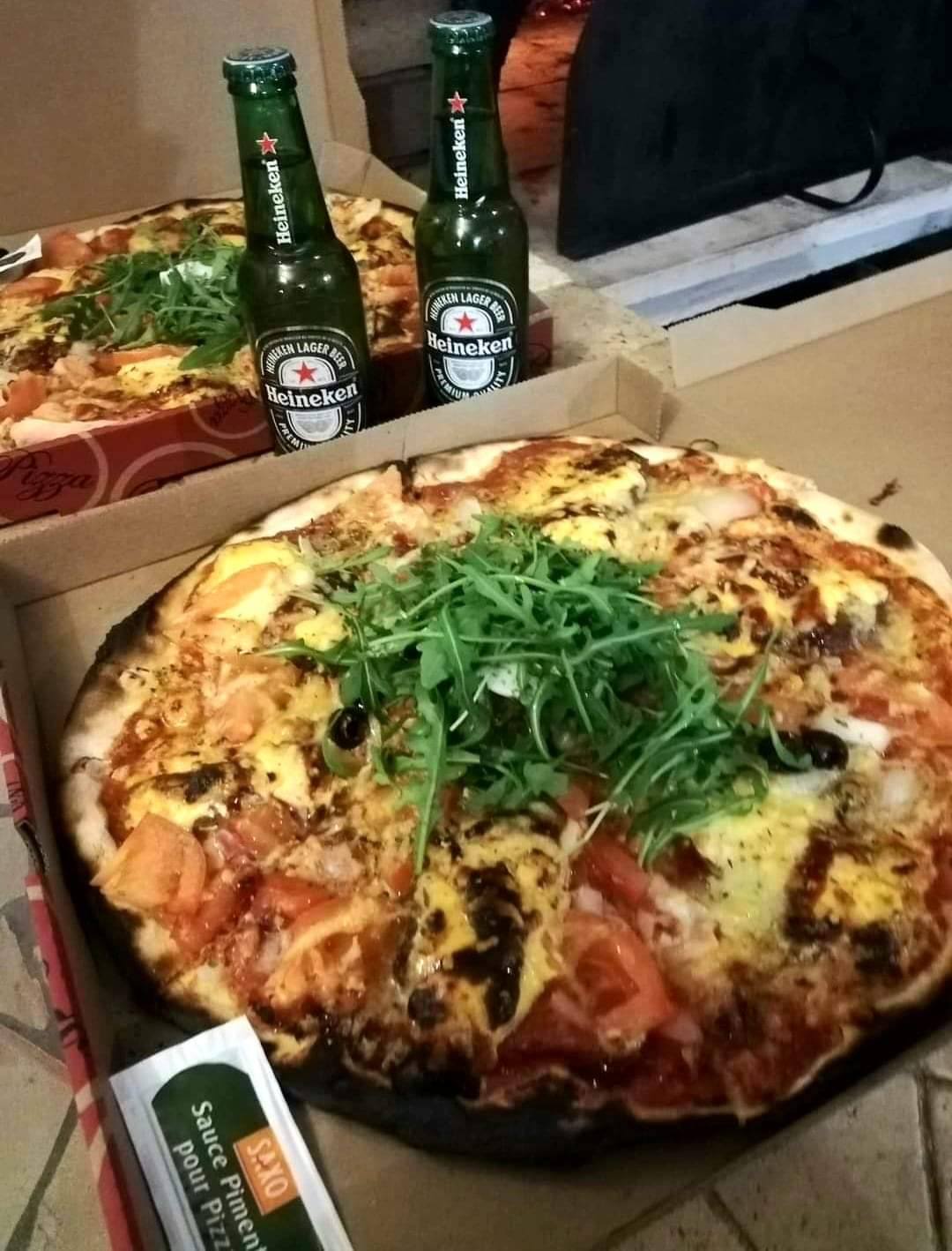 Pizza accompagnée de roquette dans son carton, ambiance soirée chez Pizzas Popeye